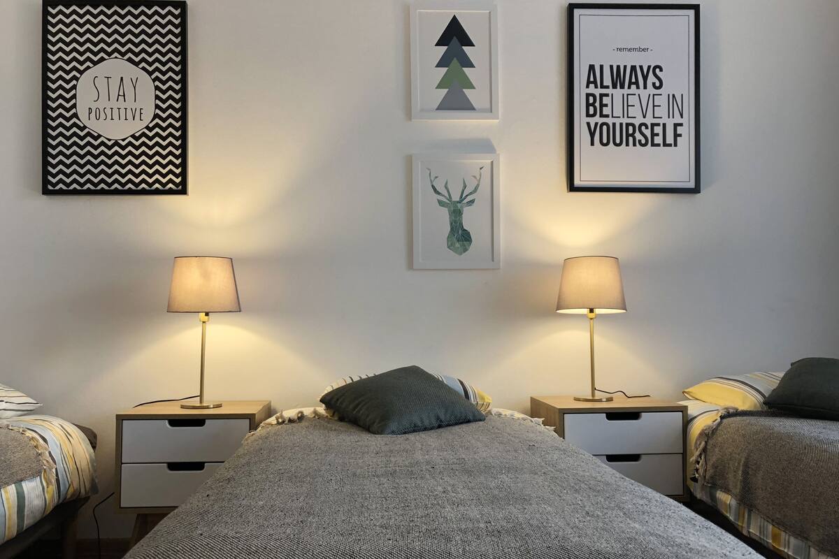Een slaapkamer met een groot bed, twee nachtkastjes en drie kunstwerken aan de muur.