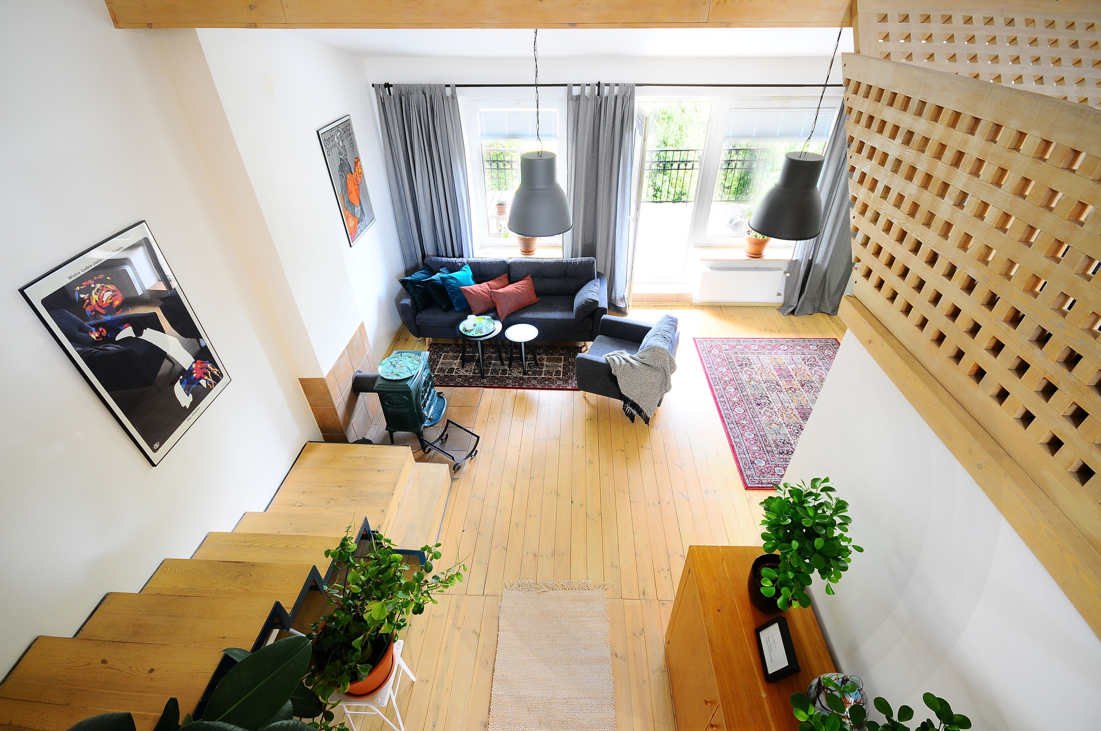 A modern living room with a sofa, a coffee table, and a dining area with a table and chairs. There are potted plants and a wooden floor.