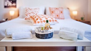 A neatly made bed with white and orange patterned pillows, a wicker basket labeled 'Salle de Bain' with toiletries, and white towels on a bedside table. - Baia Verde Concy's Apartment Gallipoli (Gallipoli)