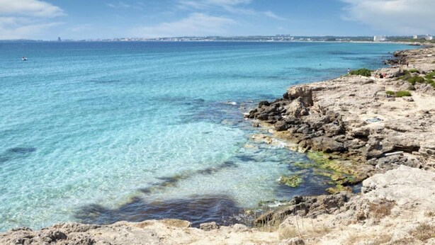 A coastal landscape with clear turquoise waters, rocky shoreline, and distant cityscape. - Baia Verde Concy's Apartment Gallipoli (Gallipoli)