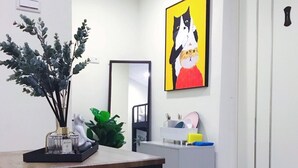 A modern room with a wooden table, a mirror, a painting of cats, and a plant. - Ha Ha Cat Home Ximending (Taipei)