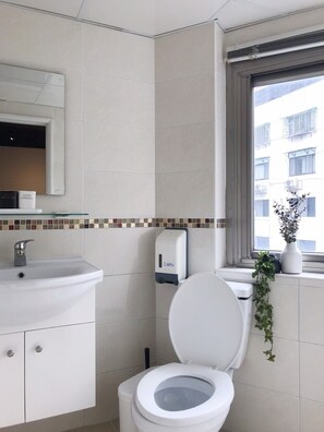 A bathroom with a toilet, sink, and a window with a view of buildings. - Ha Ha Cat Home Ximending (Taipei)