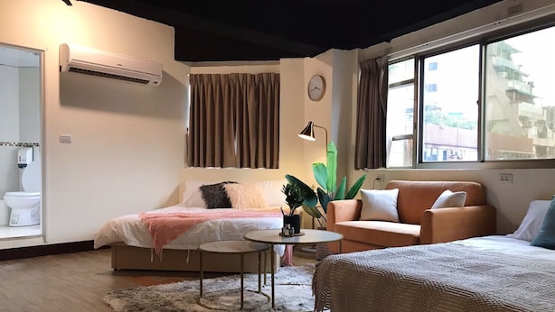A modern hotel room with a bed, a sofa, a small table, and a potted plant. - Ha Ha Cat Home Ximending (Taipei)