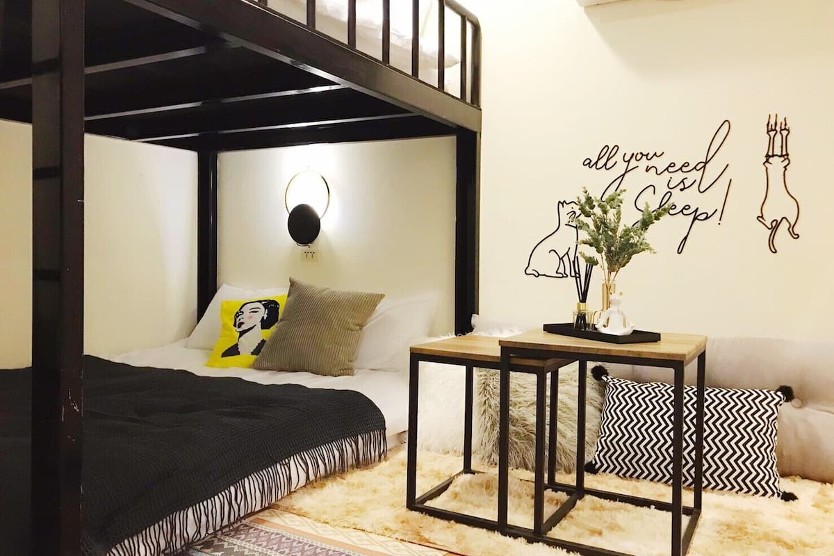 A bedroom with a bunk bed, a bedside table with a vase, and a wall decoration.