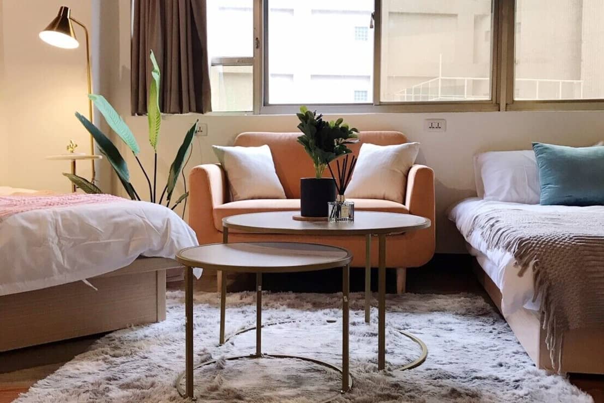 A cozy room with a round table, two sofas, a fluffy rug, and a large window with curtains.