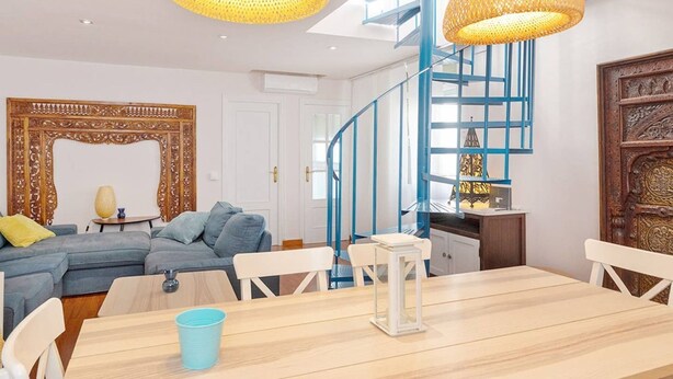 Een moderne woonkamer met een blauwe trap, een eettafel en een grote spiegel.