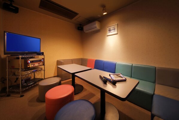 Una habitación con televisión, computadora, mesa y banco.