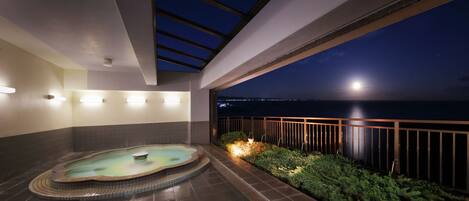 A rooftop terrace with a hot tub, a small pool, and a view of the night sky and city lights.