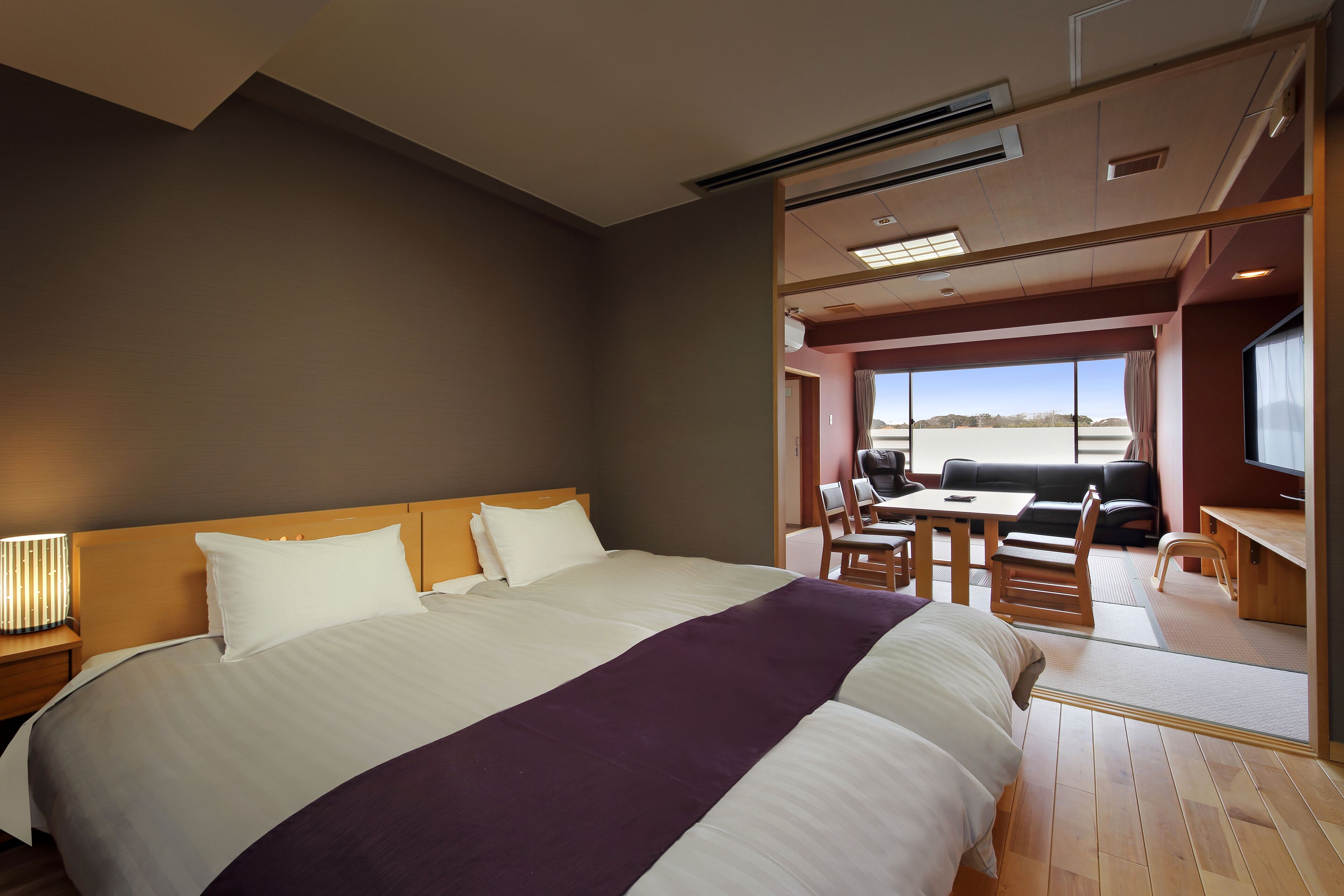 Quarto de hotel moderno com uma cama grande, uma escrivaninha e vista para o exterior.