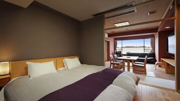 Quarto de hotel moderno com uma cama grande, uma escrivaninha e vista para o exterior.