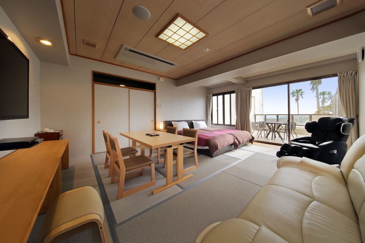 A hotel room with tatami flooring, a traditional Japanese-style room, a sofa, a massage chair, a bed, and a sliding door.