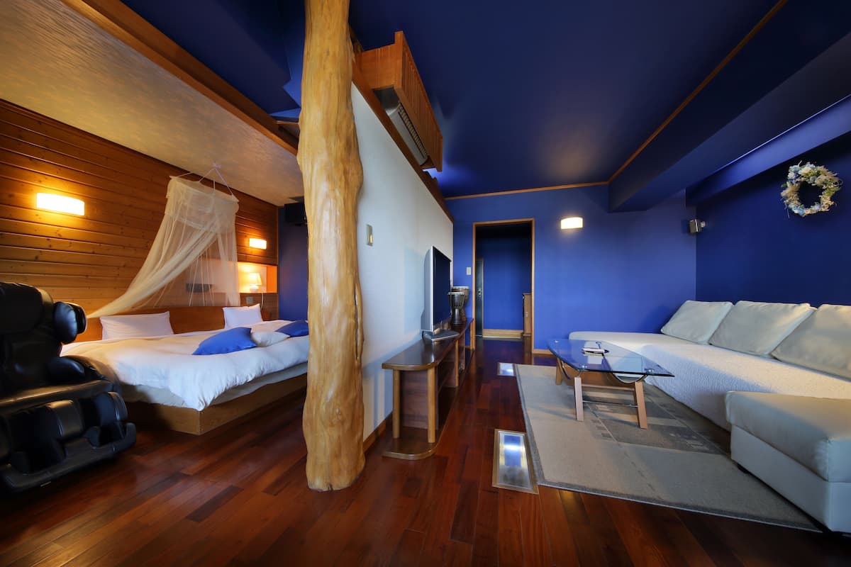 A modern room with a bed, massage chair, and a sofa.