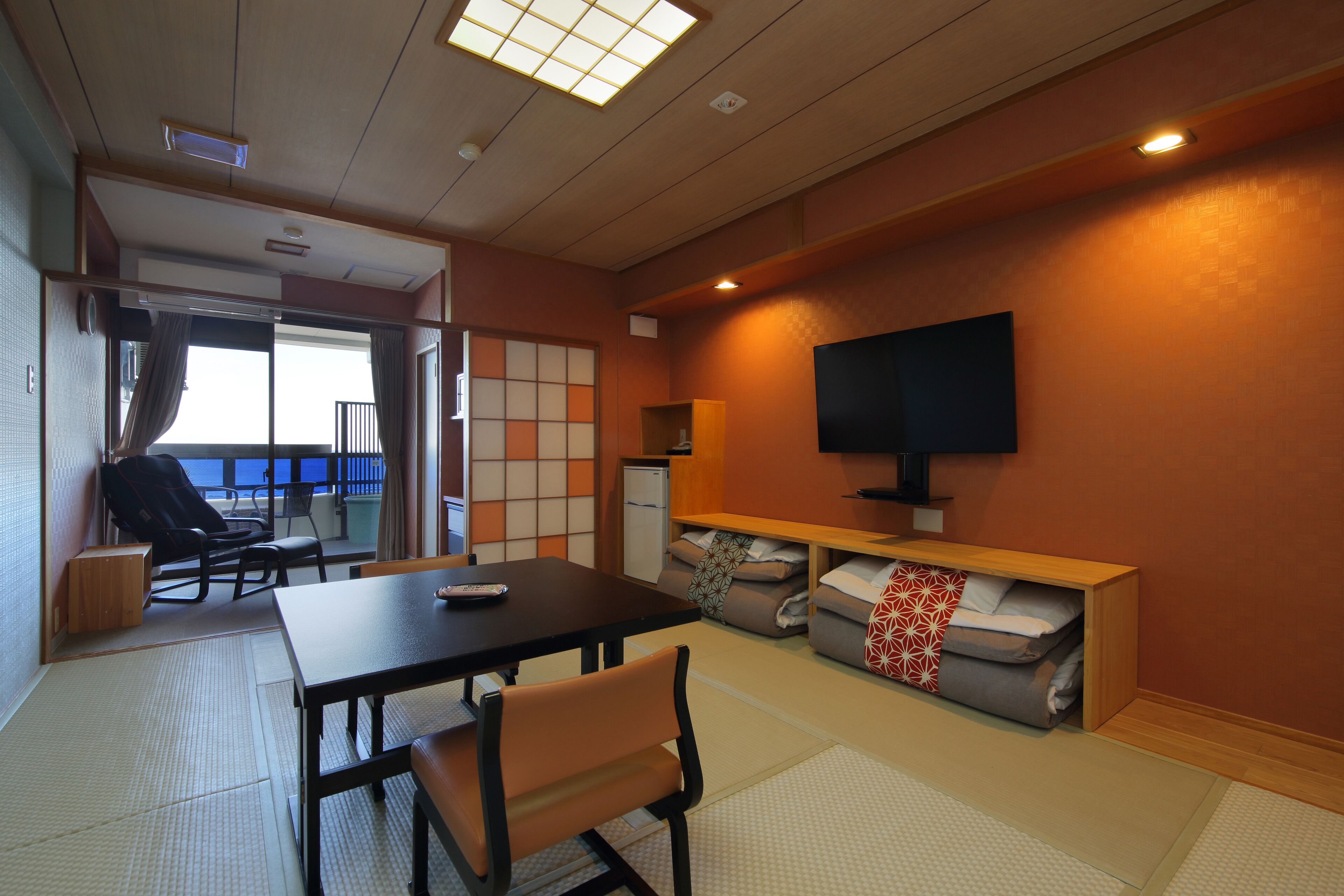 Un espacio habitable compacto con zona de comedor, sofá, televisión y vistas a través de una puerta corredera.