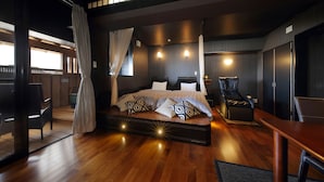 A spacious bedroom with a large bed, a sitting area with a chair, and a view of the outside. - Yumemisaki (Minamiboso)