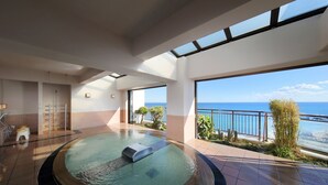 A modern indoor swimming pool with a view of the sea, a sunlit room with a large window, and a small seating area. - Yumemisaki (Minamiboso)
