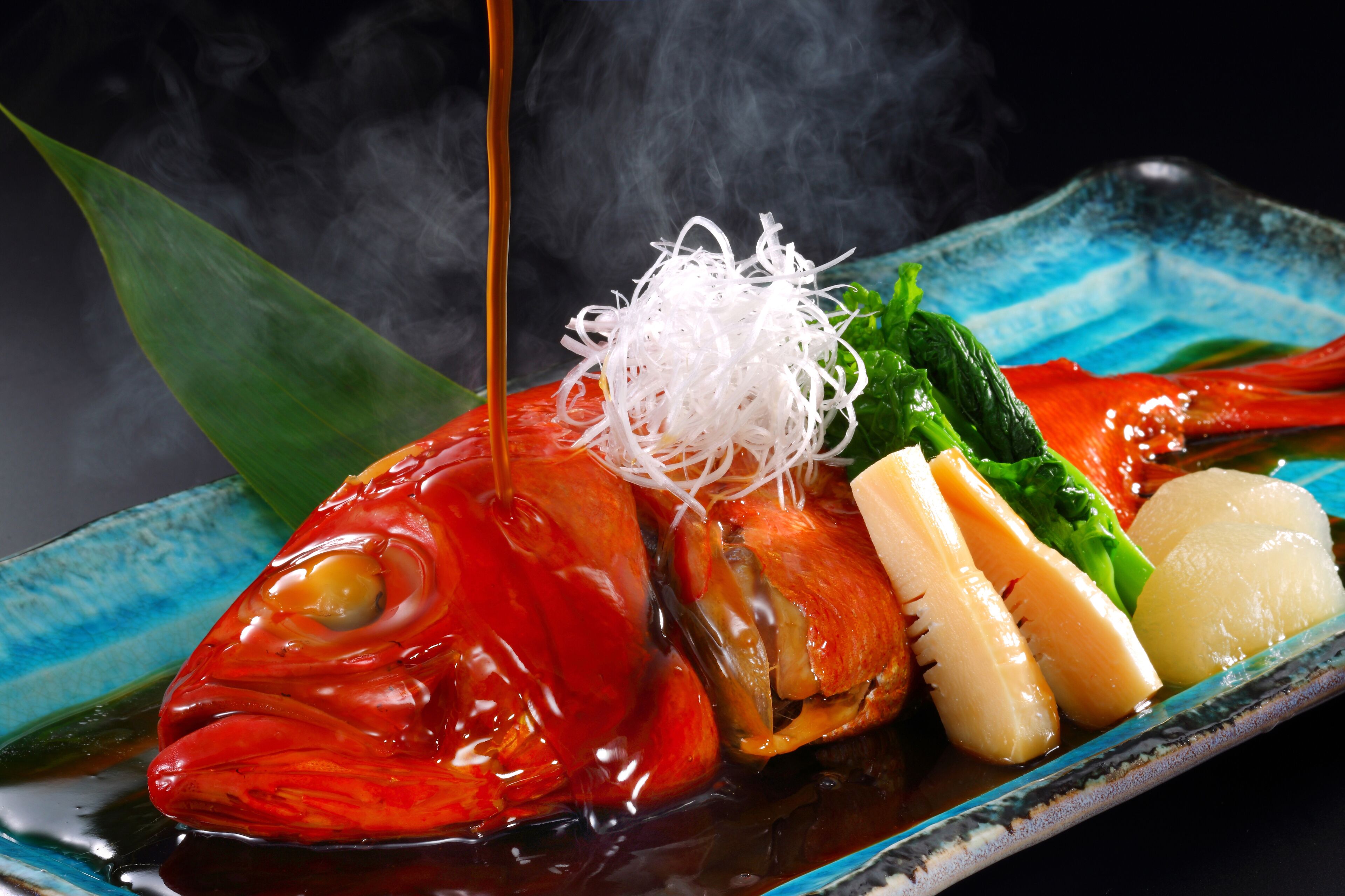 A seafood dish with a lobster tail, vegetables, and a sauce being poured over it.
