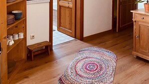 A hallway with wooden shelving, a door, a small bench, and a colorful rug. - Ferienwohnung, Nr. 2, 48 qm Dachgeschoss, 1 Separates Schlafzimmer (Bad Endorf)