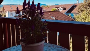 A balcony with a potted plant and a table with a floral tablecloth. - Ferienwohnung, Nr. 2, 48 qm Dachgeschoss, 1 Separates Schlafzimmer (Bad Endorf)