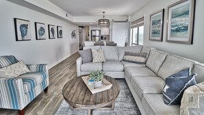 Una sala de estar moderna con un sofá modular, una mesa de centro y un comedor al fondo.