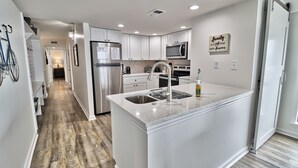 Una cocina moderna con armarios blancos, electrodomésticos de acero inoxidable y encimera de granito.