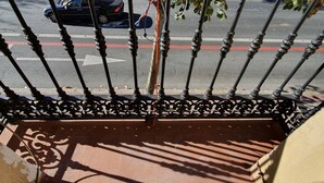 Une vue depuis un balcon doté d’une balustrade en métal, donnant sur une rue.