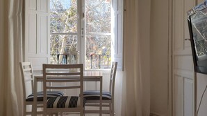 Une pièce comprenant une table à manger et des chaises, une fenêtre donnant sur des arbres et une porte dotée d’un miroir.