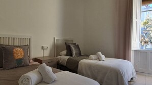 Une chambre d’hôtel avec deux lits, une table de chevet, un radiateur et une fenêtre donnant sur l’extérieur.
