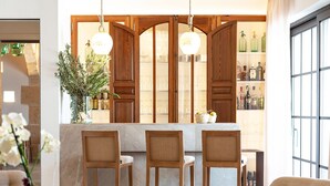 A modern kitchen with wooden cabinets, a marble countertop, and a dining area with three chairs. - Ynaira Hotel & Spa (Ariany)