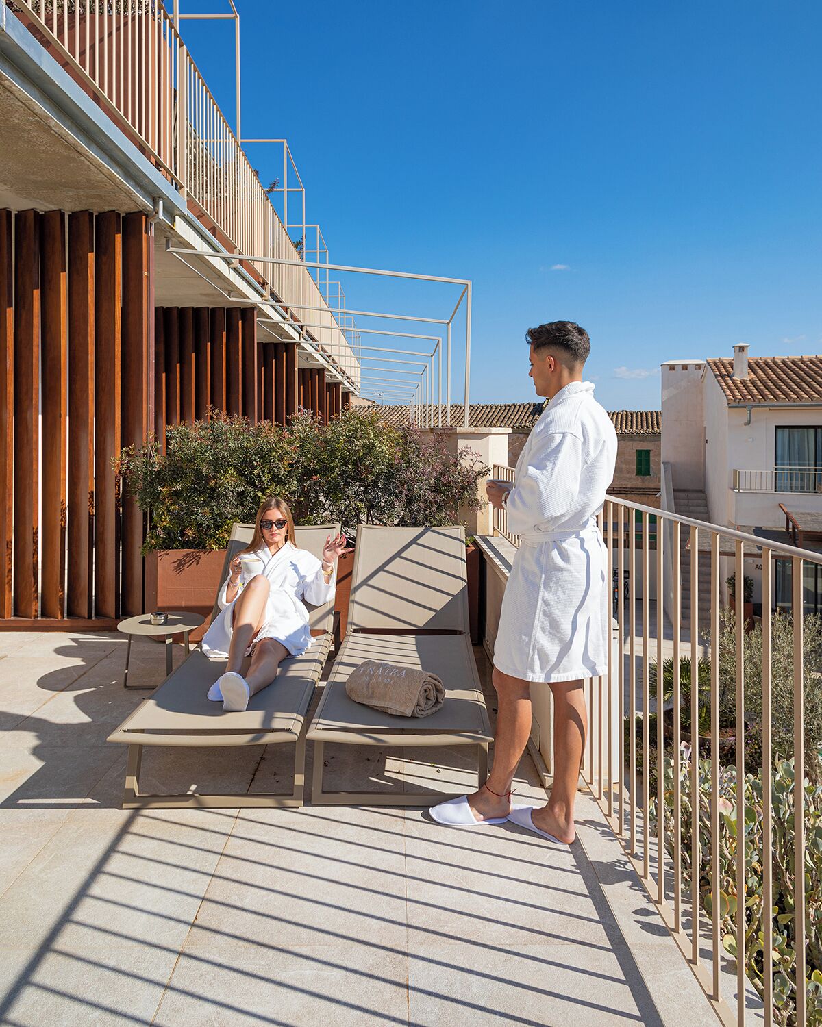 Terraza en la azotea con sillones de sol, una persona de pie y una mujer relajándose.
