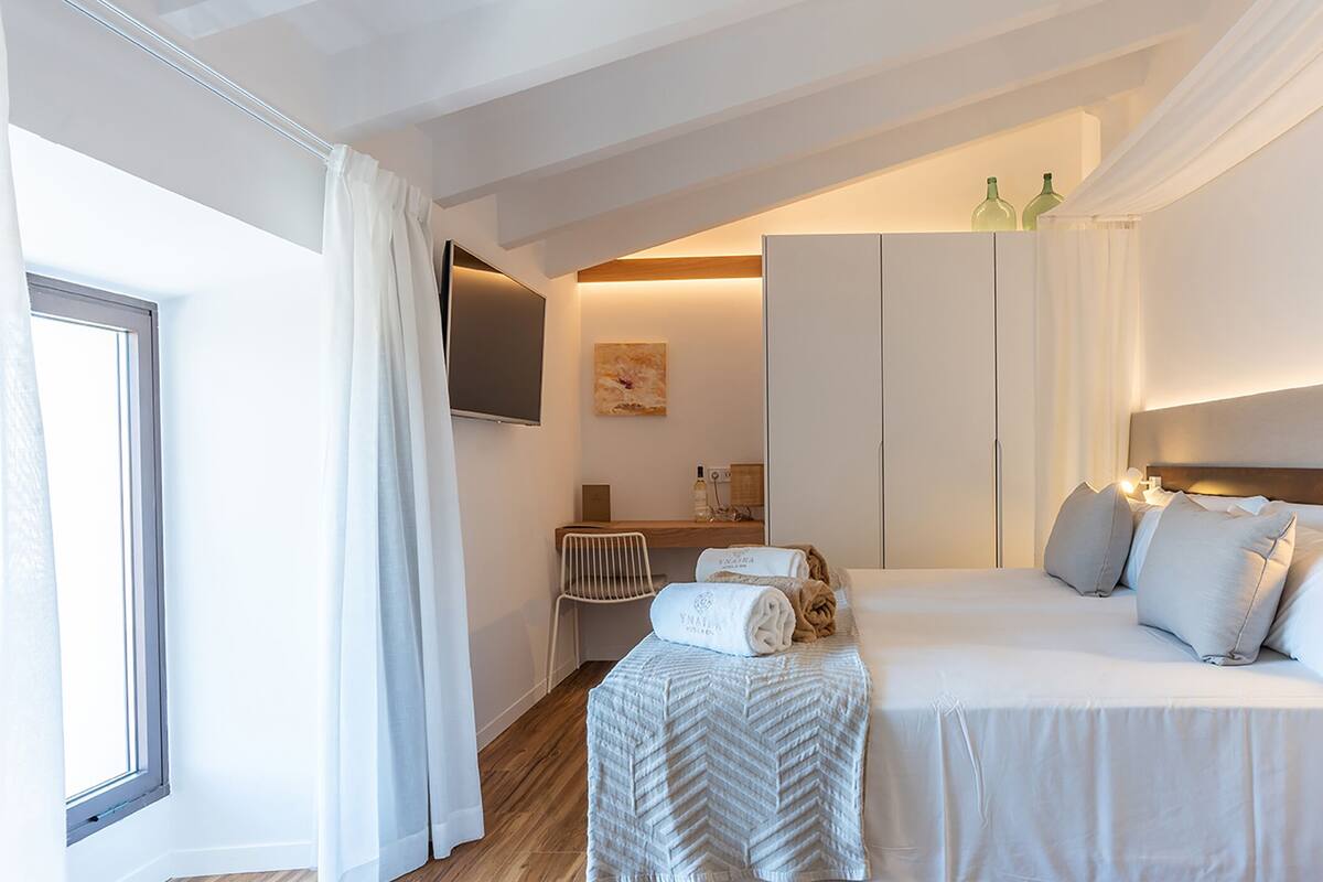 A hotel room with a bed, a chair, a desk, and a television.