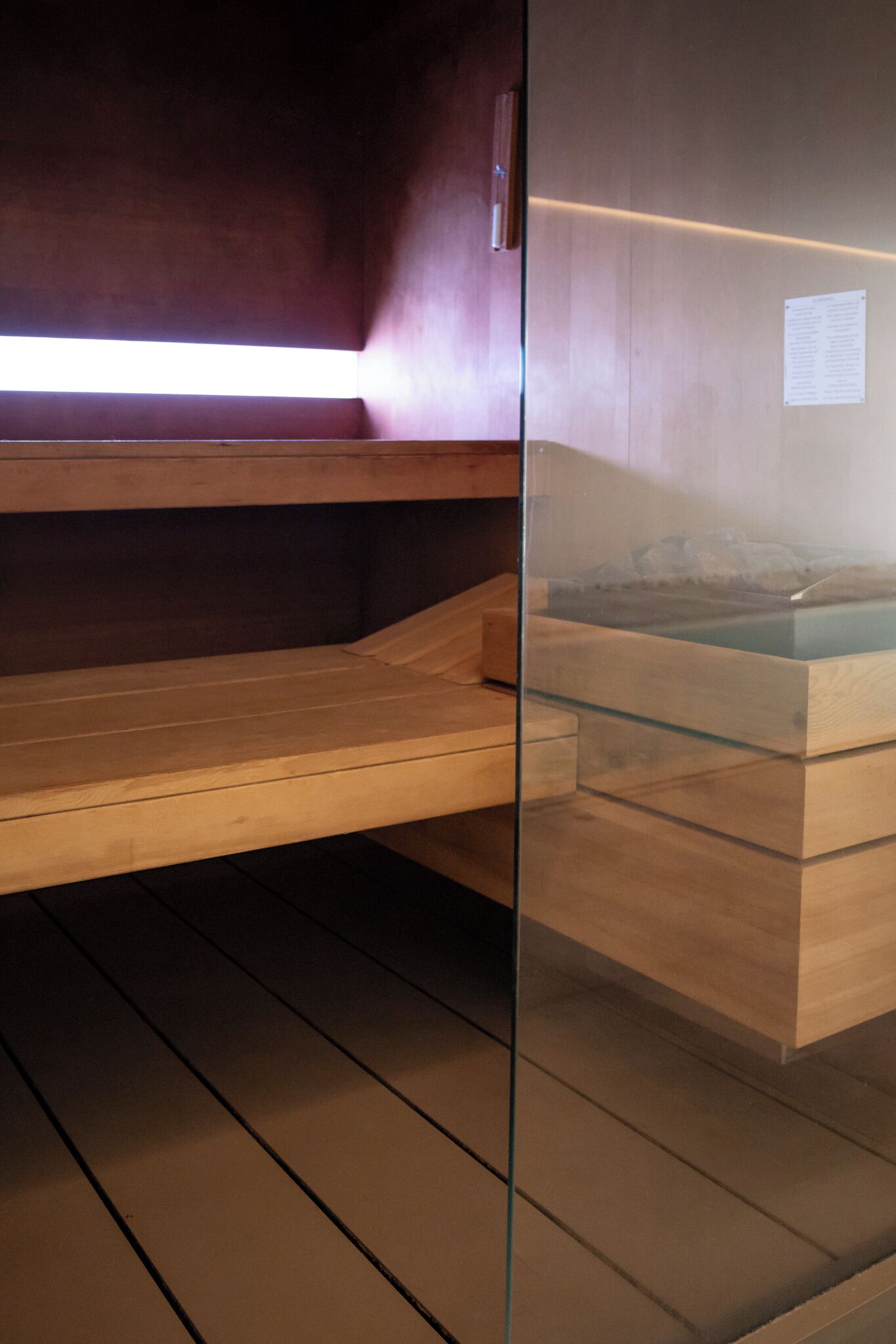 Una sauna amb bancs de fusta i una separació de vidre.