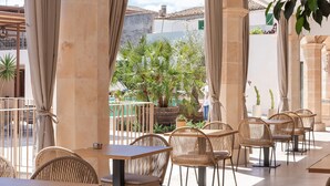 An outdoor cafe with wicker furniture, large pillars, and potted plants. - Ynaira Hotel & Spa (Ariany)