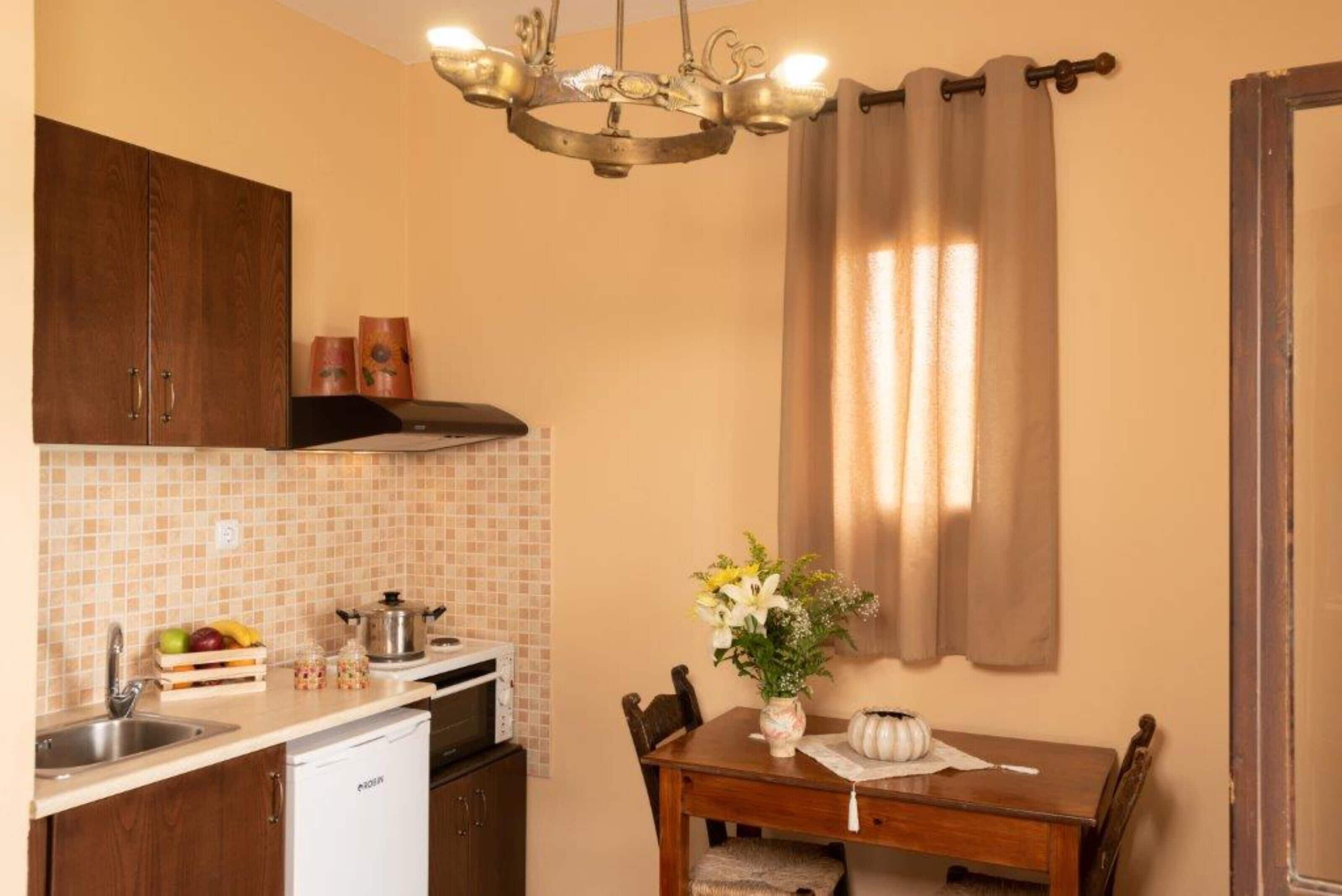 A compact kitchen with a wooden table, a white dishwasher, and a tiled backsplash.