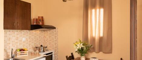 A compact kitchen with a wooden table, a white dishwasher, and a tiled backsplash.
