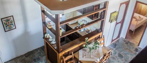 A dining area with a wooden table and chairs, a kitchen area with a sink and cabinets, and a stone floor.