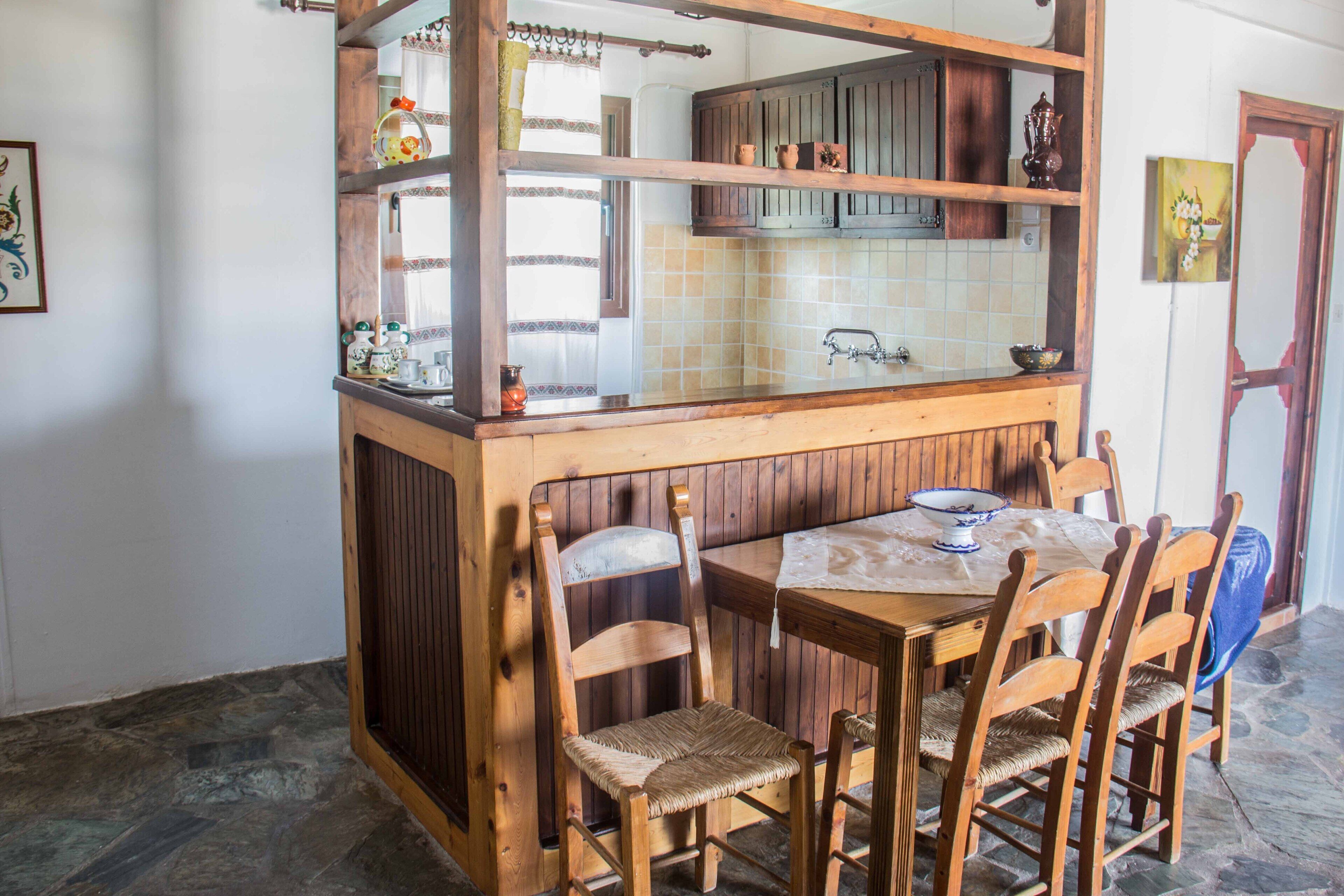 Una cocina rústica con una isla de madera, una mesa de comedor con sillas y un salpicadero de azulejos.