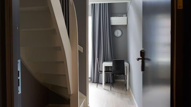 A staircase leading to a room with a desk, chair, and a clock on the wall.