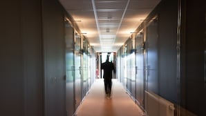 A corridor with glass doors on both sides, leading to a room with a visible window.