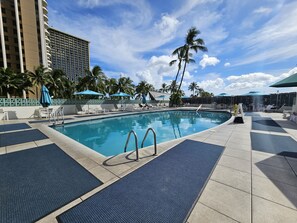 Relax by the pool surrounded by comfortable lounge chairs and shaded umbrellas.