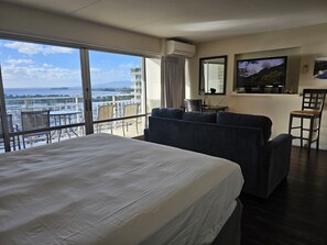 Relax in this spacious room with a large bed, sofa, and chairs, featuring a wall-mounted TV and a stunning sea view.