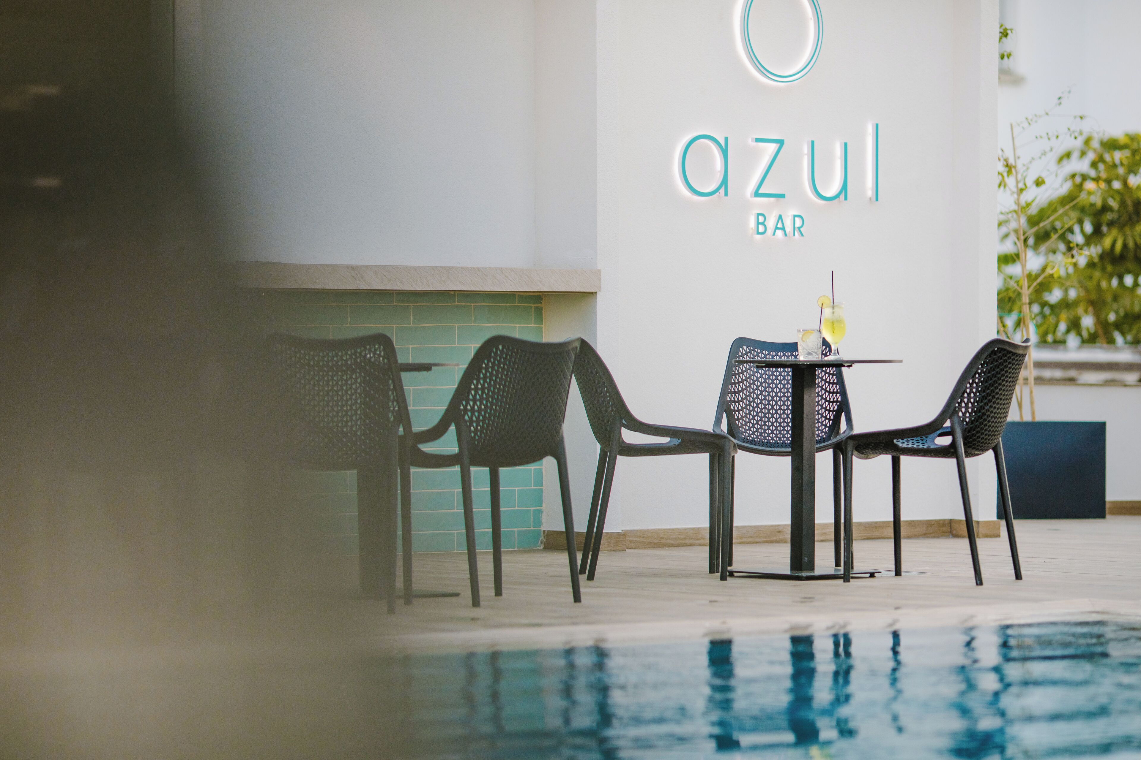 An outdoor seating area with a pool, chairs, and a table with drinks.