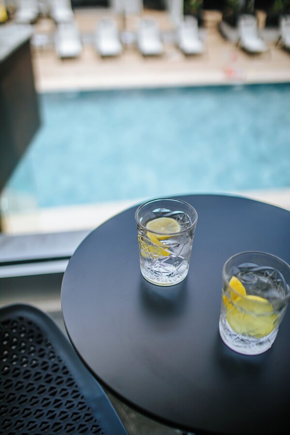 Two glasses of water with lemon slices on a round table near a poolside.