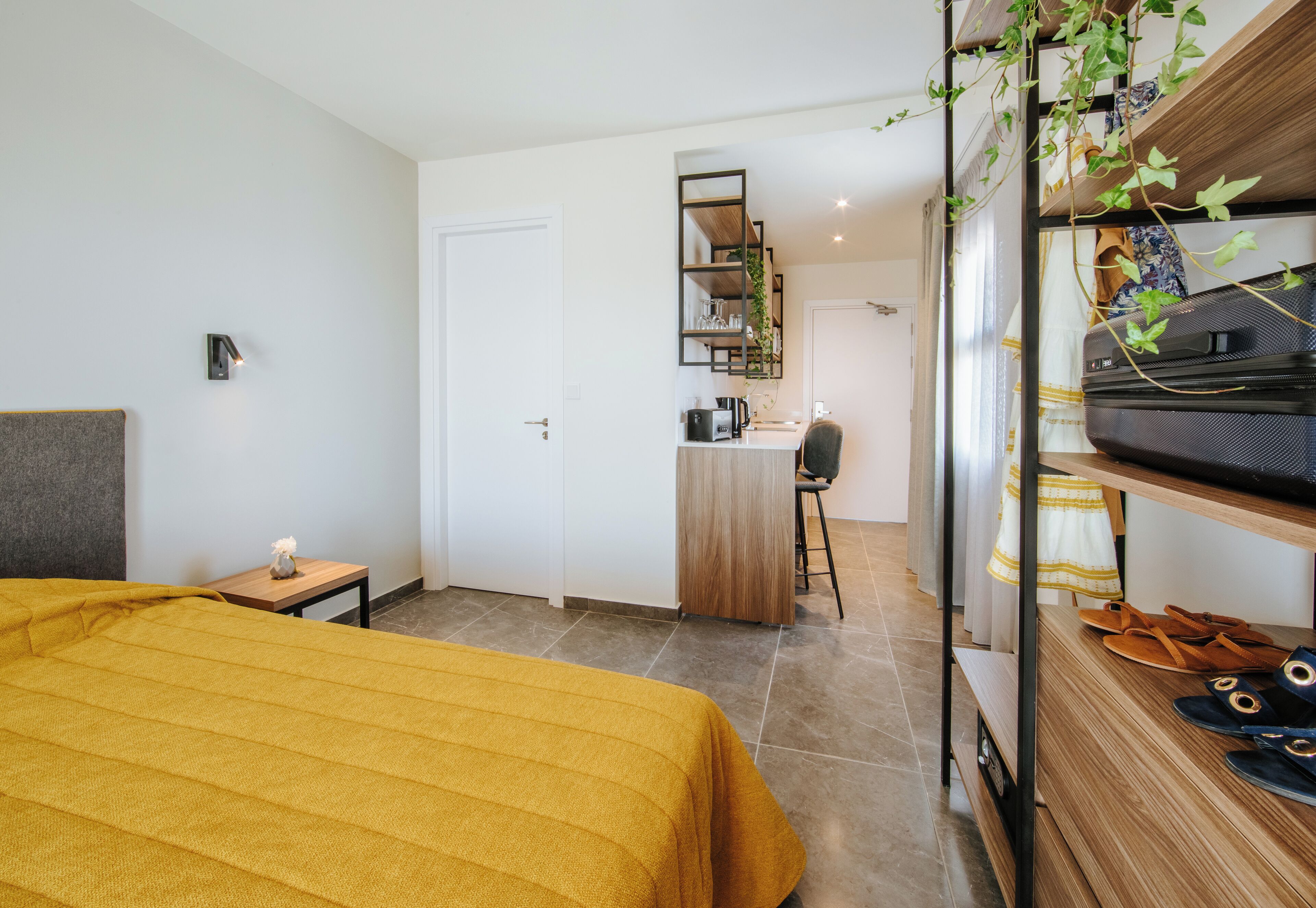 A hotel room with a bed, a desk, a chair, a wardrobe, and a shoe rack.