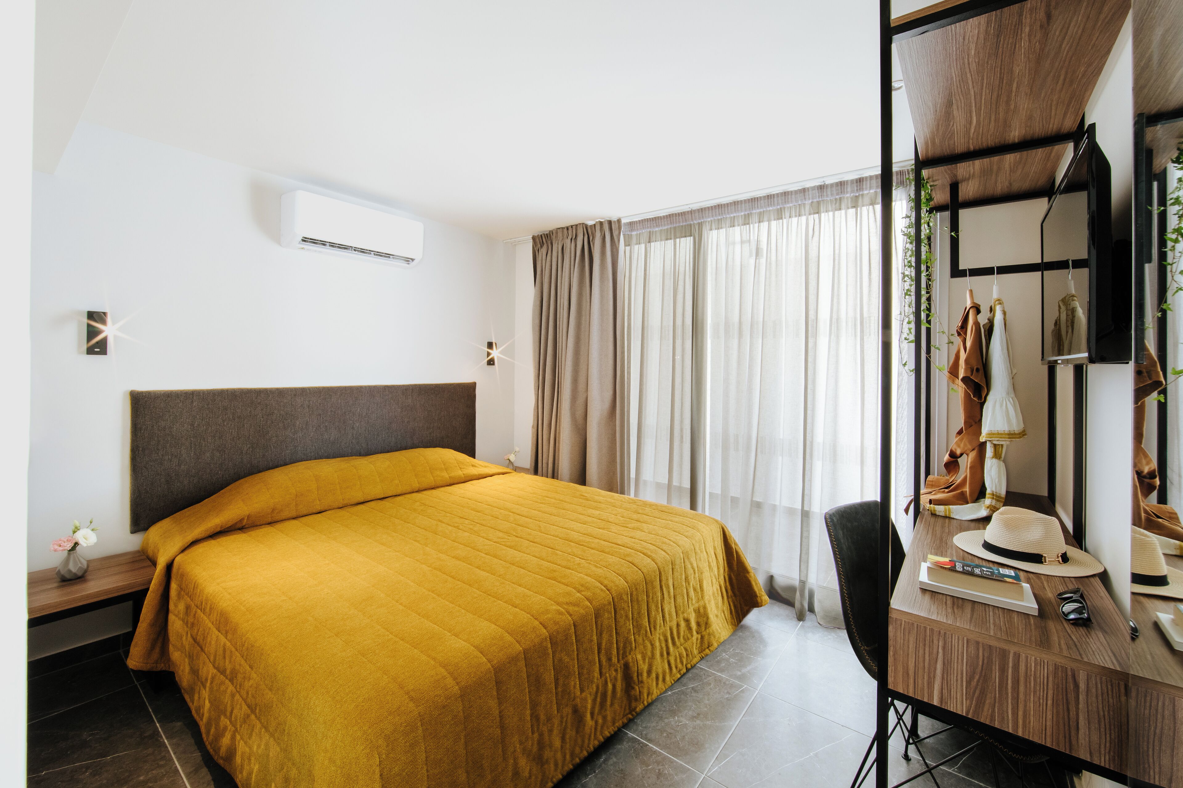 Una habitación de hotel con una cama grande, un escritorio con espejo y una ventana con cortinas.
