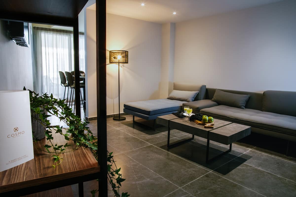 Un salon moderne avec un canapé, une table basse sur laquelle sont disposés des fruits, une lampe sur pied et une plante.