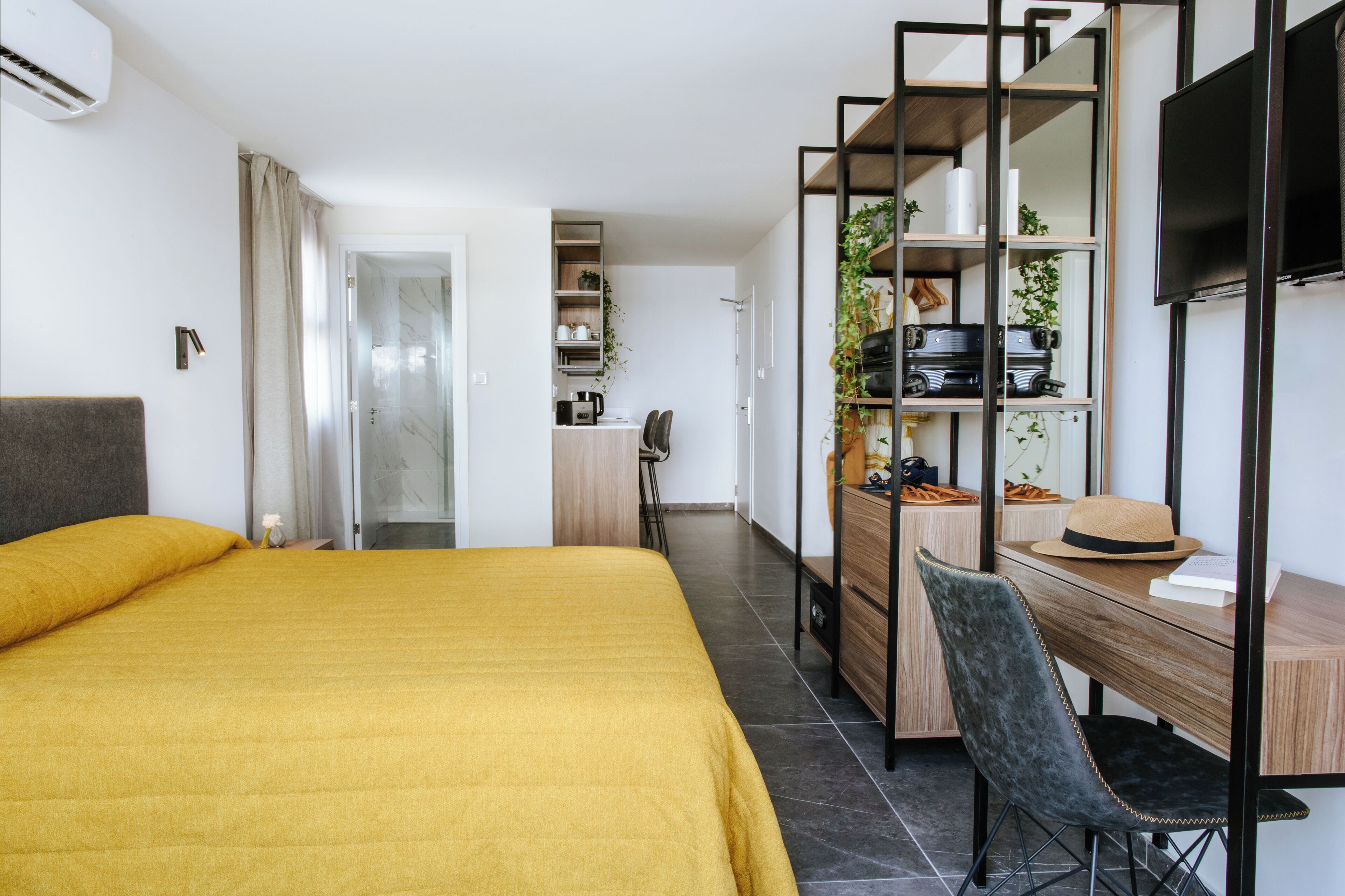 A hotel room with a bed, a desk, a chair, a TV, and a wardrobe.