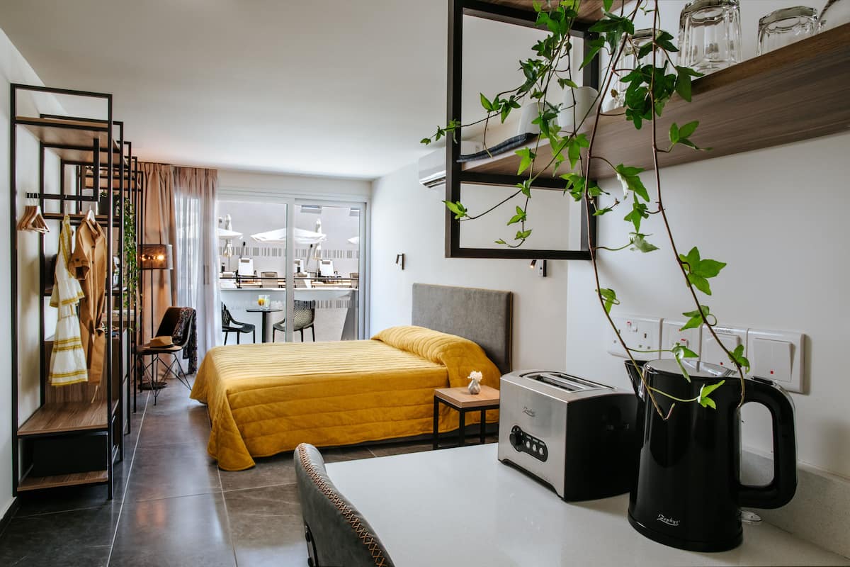 Une chambre d’hôtel de taille réduite, comprenant un lit, une petite table, une bouilloire et une chaise.