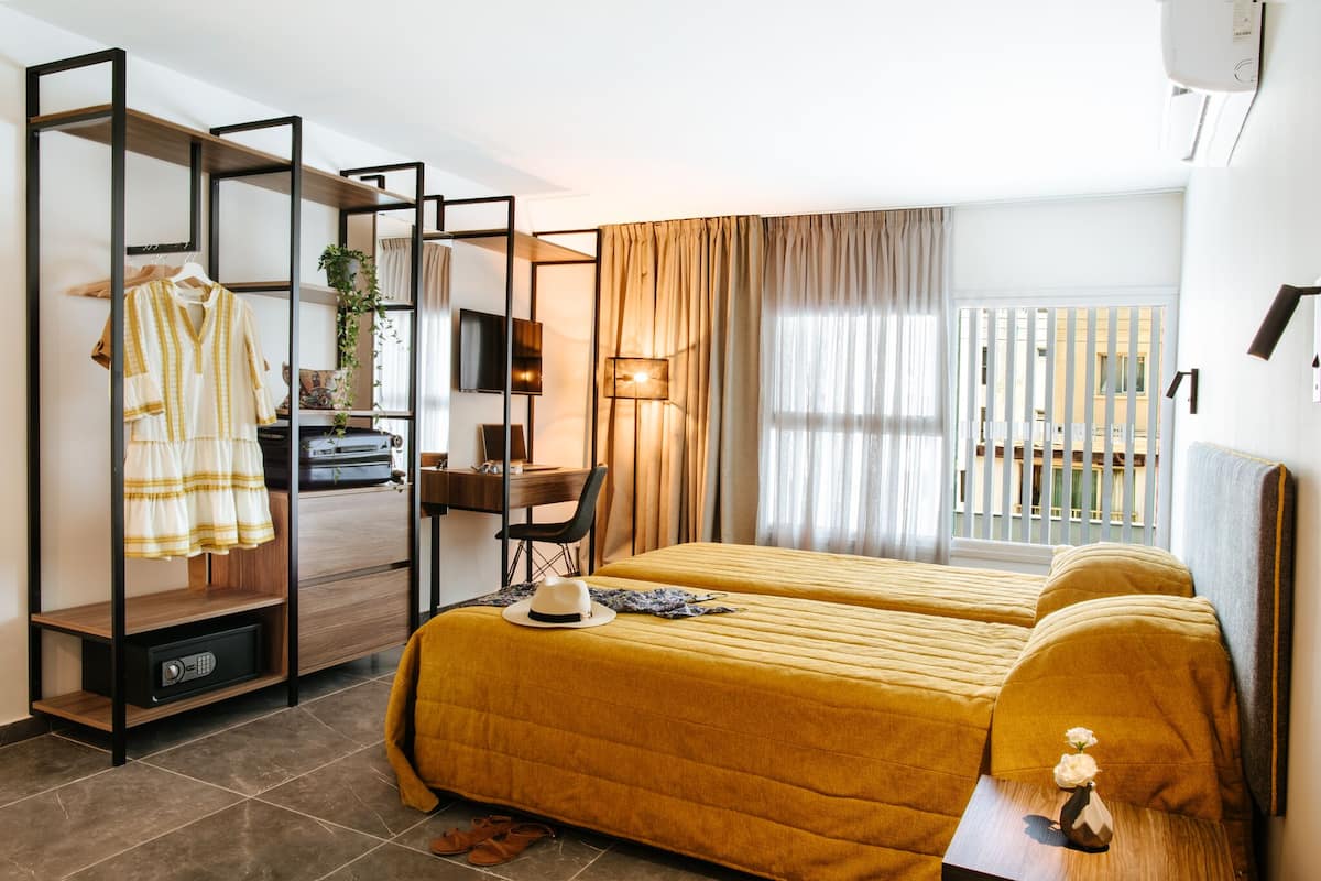 Une chambre d’hôtel avec deux lits, un bureau, une télévision et une armoire.