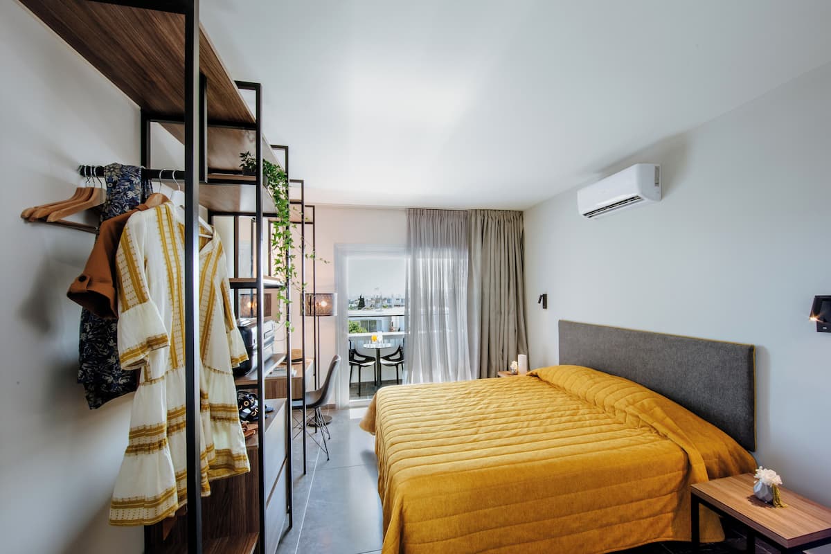 Une chambre d’hôtel avec un lit, un bureau, une chaise et un balcon offrant une vue.