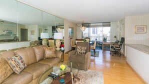 Een ruime woonkamer met een leren bank, een glazen salontafel en een eethoek met een tafel en stoelen.